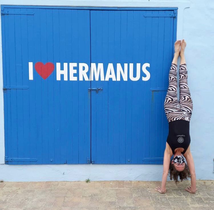 Happy acrobat enjoying the blue I Love Hermanus sign, near Cape Town, South Africa